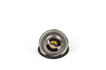 New car thermostat on a white isolated background next to a rubber gasket. Repair kit of spare parts for the replacement of the thermostat in the engine cooling system