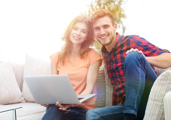 young couple of students with laptop sitting on the couch