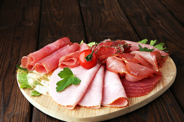 Food tray with delicious salami, pieces of sliced ham, sausage, tomatoes, salad and vegetable - Meat platter with selection