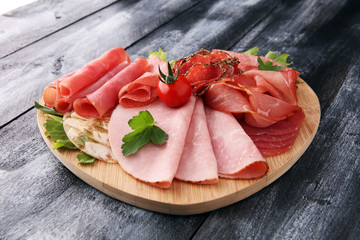 Food tray with delicious salami, pieces of sliced ham, sausage, tomatoes, salad and vegetable - Meat platter with selection