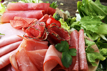Food tray with delicious salami, pieces of sliced ham, sausage, tomatoes, salad and vegetable - Meat platter with selection