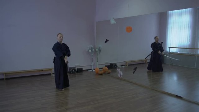 The Samurai in Kimono Leads Shadow Fight with the Help of the Katana Sword in the Hall with Mirrors on Helouin