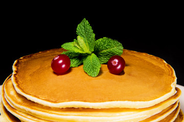 Delicious breakfast of fresh baked pancakes with cranberries and mint on a black background