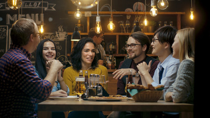 Diverse Group of Young People Have Fun in Bar, Talking, Telling Stories and Jokes. They Drink...