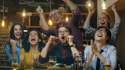 Diverse Group of Friends Watches TV in the Sporstbar. Beautiful Young People Drink, Have Fun and Cheer for their Team. © Gorodenkoff