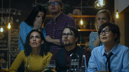 Young People in the Bar Watch TV Suddenly Breaking News Show that Tragic Events Unfold. Young...