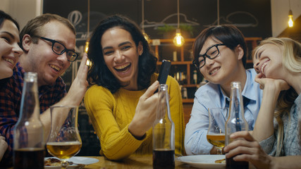 In the Bar/ Restaurant Hispanic Woman Makes Video Call with Her Friends. Group Beautiful Young People in Stylish Establishment.