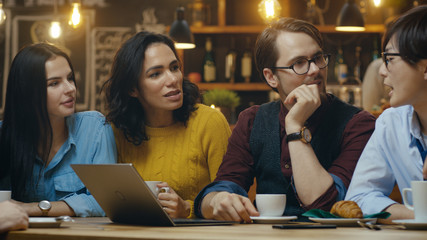 Diverse Group of Colleagues Has Business Lunch at the Bar/ Restaurant, They Think about Solving Problems and Use Laptop Computer. Beautiful Young People in Stylish Establishment.