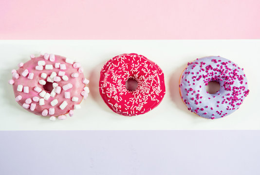 three donuts red pink purple on a three-color background