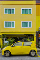 желтый автомобиль на фоне желтого малоэтажного дома 