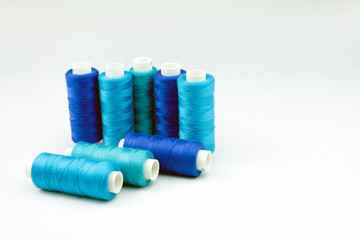 blue threads on reels selective focus, white background
