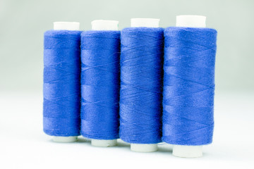 blue threads on reels selective focus, white background