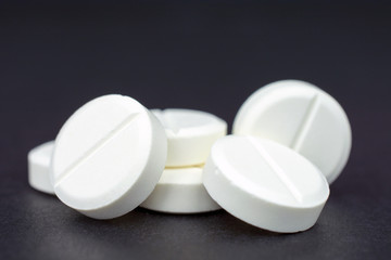 white round tablets painkiller copy space, black background, selective focus