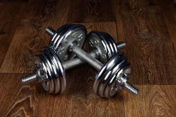 two iron dumbbells on a wooden floor, old school heavy dumbbell training