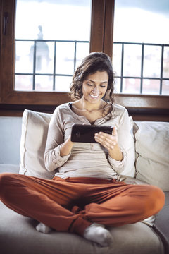A young woman holding a Tablet PC on the sofa