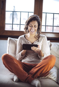 A young woman holding a Tablet PC on the sofa