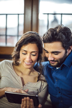 Young Couple Sitting On Sofa Using Digital Tablet