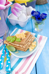 Homemade traditional pancakes with parmesan and basil for spring carnival. Italian breakfast. Bright flowers of tulips. Blue background. A free place for text or a postcard.