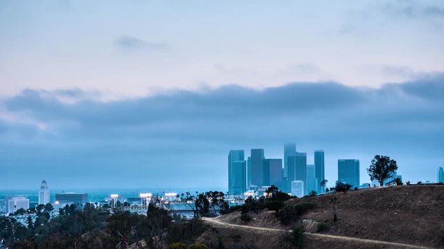 Marine layer clouds moving over downtown Los Angeles skyline at twilight - night
