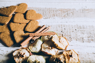 cookie hearts and chocolate with cinnamon sticks and slices of dried apples with text space on wooden background