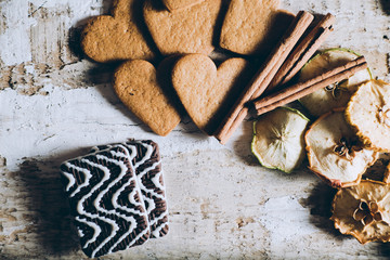 cookie hearts and chocolate with cinnamon sticks and slices of dried apples with text space on wooden background