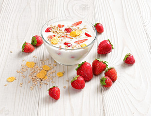 Bowl of homemade yogurt with muesli and fresh strawberry on wooden table. Fresh yogurt. Healthy food concept. High resolution product.
