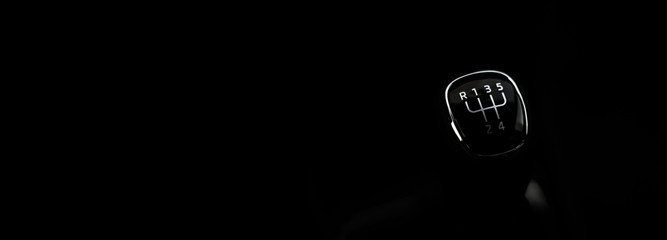 Manual transmission gear shift, on dark backgroun. For text.