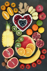 Super food for healthy eating with fresh fruit, vegetables, nuts and spice high in antioxidants, anthocyanins, fibre, vitamins and minerals. On slate top view.