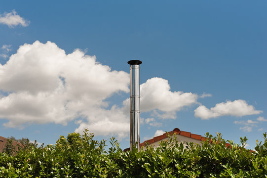 Ein gl&auml;nzender Schornstein aus Edelstahl unter blauem Himmel