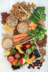 Health food for a high fibre diet with whole wheat pasta, grains, legumes, nuts, fruit, vegetables and cereals with foods high in omega 3,  antioxidants and vitamins. Rustic background top view.