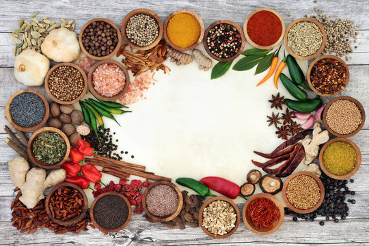 Spice and herb border with fresh and dried herbs and spices on parchment paper and rustic wood  background. Top view.