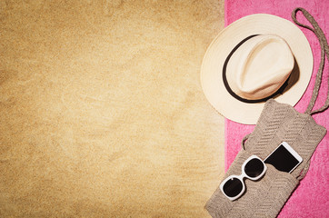 Top view of sandy beach with towel frame and summer accessories. Background with copy space and visible sand texture. Border composition made of towel