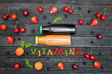Fototapeta na wymiar Two bottles of juice, the color inscription Vitamins and fruits. Wooden background.