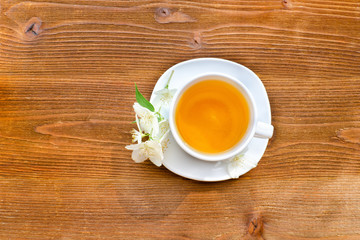 White mug of tea on a brown wooden table. Close up, top view