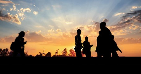 Group of business people silhouettes walking over sunset sky background. 4K UHD