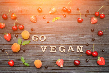Inscription Go vegan and fruits. Black wooden background. Food concept