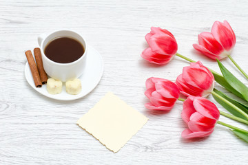Fototapeta na wymiar Pink tulips, mug of coffee and cinamon, light wooden background.