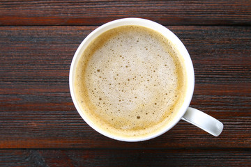 A cup of cappuccino top view, on wooden table.