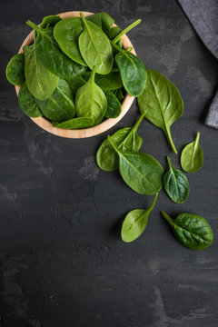 Spinach. Fresh organic spinach leaves in wooden bawl on a wooden table. Diet, dieting concept. Vegan food, healthy eating. Dark rustic style photo.