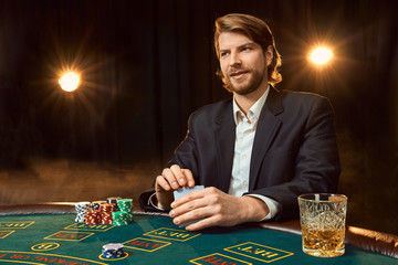 A man in a business suit sitting at the game table. Male player. Passion, cards, chips, alcohol,...