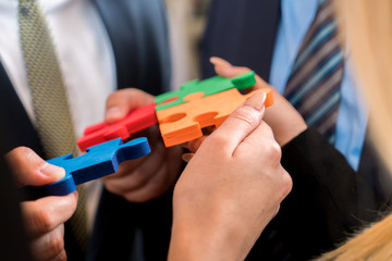 Business people solving jigsaw puzzle. Team holding colorful puzzle pieces in hands