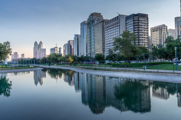 Obraz na płótnie Canvas Abu Dhabi high rise along the Corniche Boulevard near the beach park and its reflaction in the pond