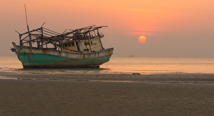 Obraz premium Wreck fisherman boat on the shore with sunset back ground. Taken at Koh Samui Thailand