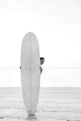 Junge lächelnde Brünette (Mädchen, Frau) mit Blick, die hinter einem weißen Surfbrett steht © Kaponia Aliaksei