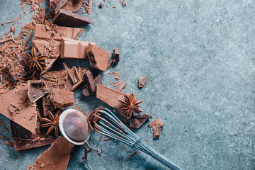 Cooking chocolate at home. Dessert ingredients, cocoa powder, cinnamon and anise stars on a marble kitchen table with a whisk for glazing and a cocoa strainer.