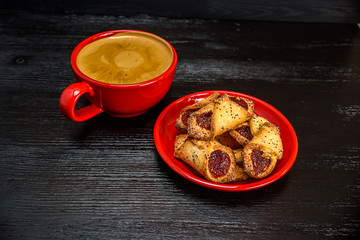 fresh aromatic coffee in a red mug and delicious pastry on a black wooden background