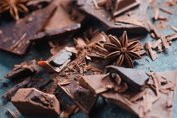 Cooking desserts and home concept. Chocolate pieces, spices, anise stars, cinnamon and cocoa on a stone background. Ingredients close-up.