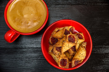 fresh aromatic coffee in a red mug and delicious pastry on a black wooden background