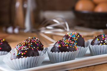 Colorful Chocolate Sprinkles on Tasty Round Chocolate Coated Cakes