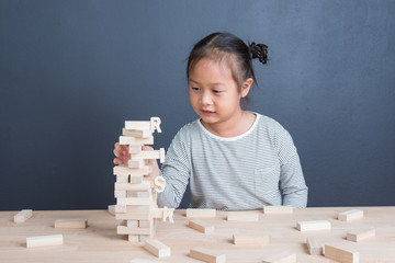Portrait of kid cute asian girl age 6 year happy to play blocks wood game with word risk